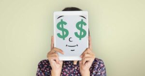 Mulher coloca página com ilustração com rosto e olhos em formato de cifrão, fazendo alusão à importância do dinheiro na saúde mental.